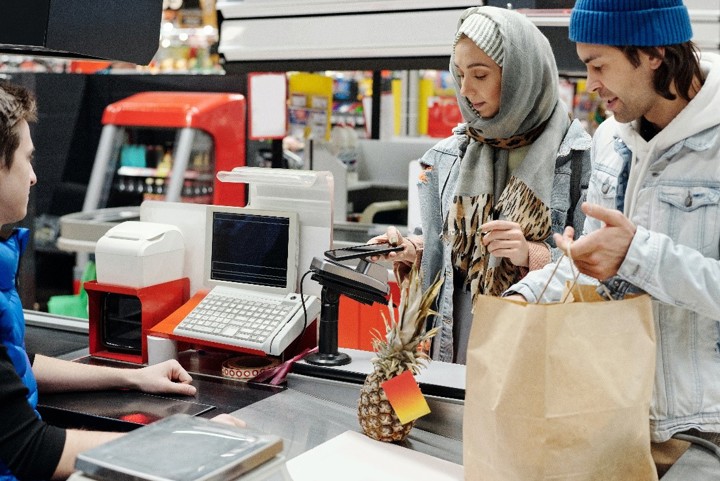 A boy and a girl are paying at the checkout counter of a store