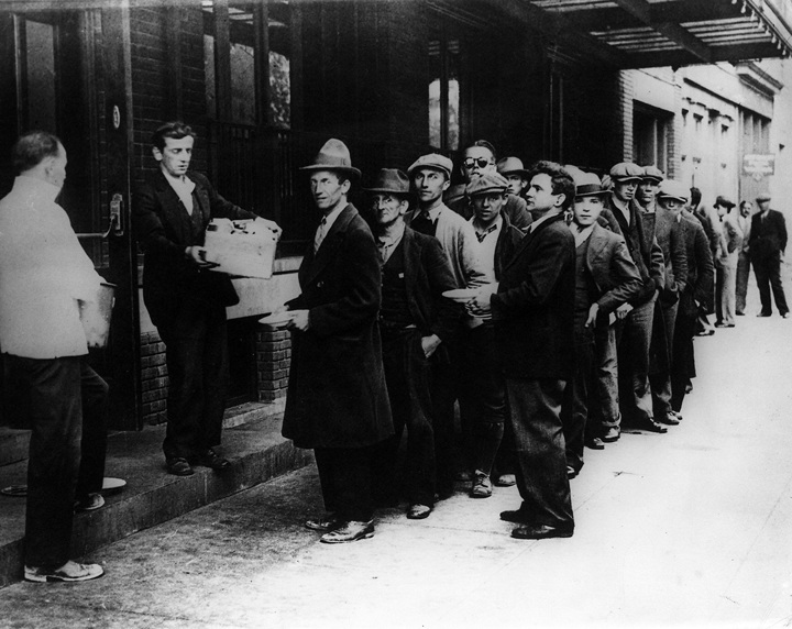 People line up for free bread and soup during the Great Depression in the 1930s. The photograph is in black and white.