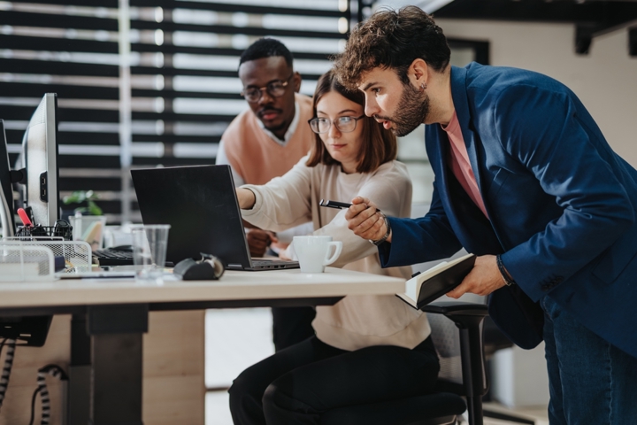 Three people looking at a computer.