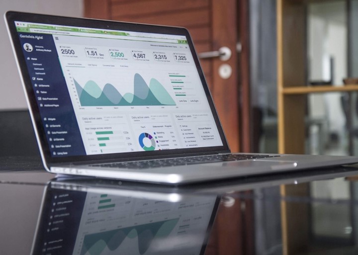 Il y a un ordinateur sur la table avec des rapports d'analyse de l'industrie sur l'écran de l'ordinateur