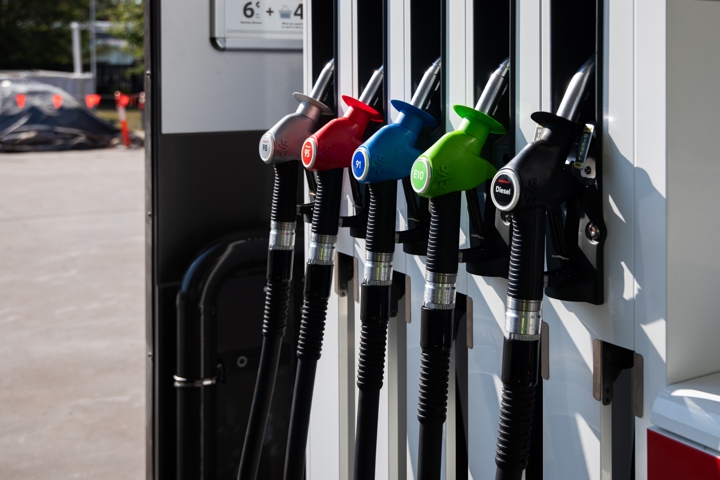 A row of coloured fuel pump nozzles at a petrol station, labelled 98, 95, 91, E10 and Diesel.