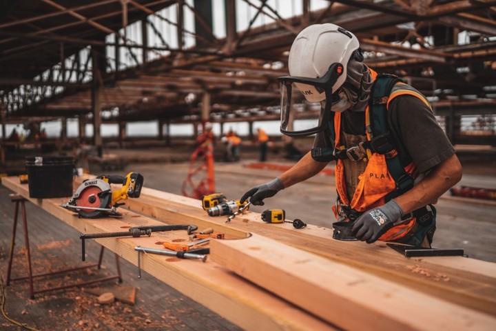 Seorang pekerja sedang memotong papan kayu