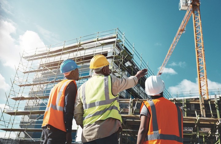 Three architects talking and pointing at a building being constructed.